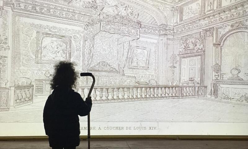 A child leaning on a cane watching Dana Levy