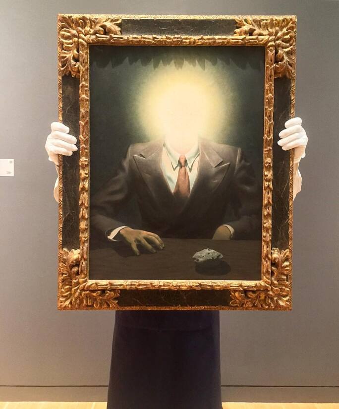 Painting of a man in a suit at a table with a spot of bright light in the place where face should be.