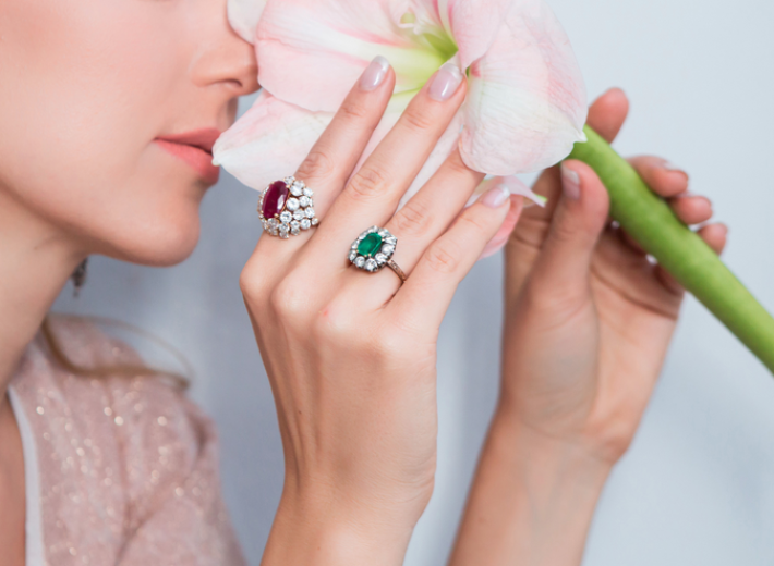 une femme portant des bagues en émeraude, diamants et rubis dans une vente aux enchères de bijoux fins en consignation