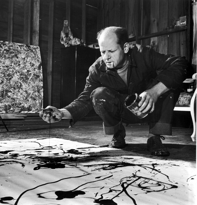 Painter Jackson Pollock, cigarette in mouth, dropping paint onto canvas.