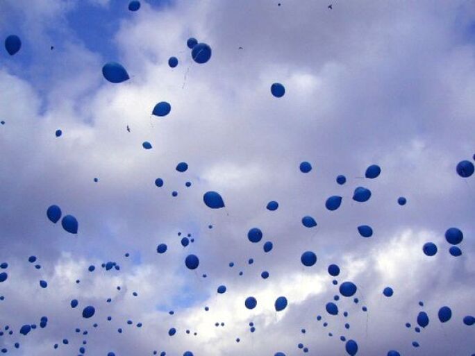 Blue balloons floating in a cloudy blue sky